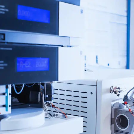 Close-up of laboratory analytical equipment with digital displays, cables, and sample holders used for chemical analysis