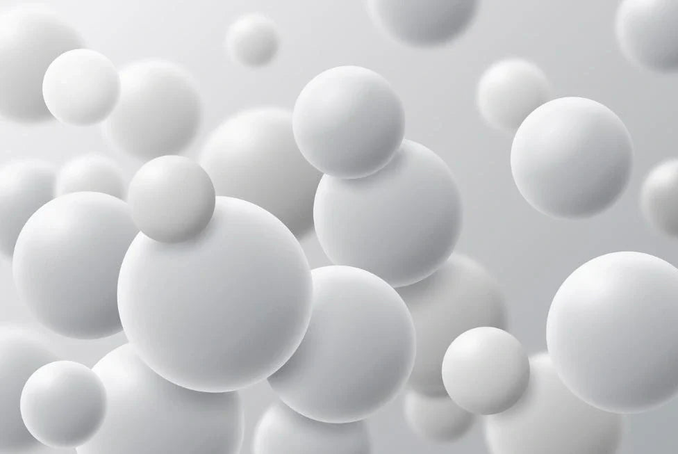 3D render of smooth white microspheres floating in a soft gray background, representing polymer or silica particles