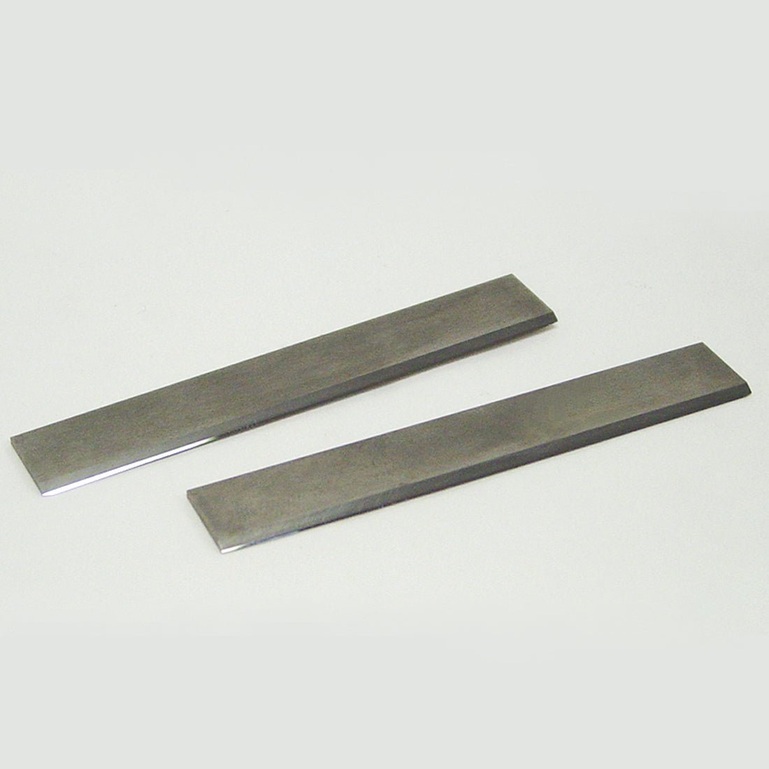 Two rectangular disposable tungsten carbide blades with sharpened edges, displayed on a light background
